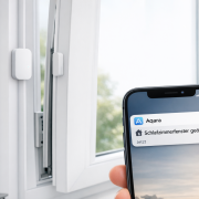 Fenster und Türen smart überwachen ohne Installation - Komplette Anleitung für Mieter Fenster und Türen smart überwachen ohne Installation – Aqara Fenstersensor an weißem Fensterrahmen mit Smartphone-Benachrichtigung für smarte Fensterüberwachung ohne Installation