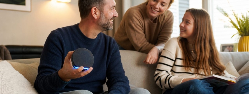 Alexa und Google Home zusammen nutzen: So geht's – Familie im Wohnzimmer mit Amazon Echo Pop und Google Nest Mini nebeneinander — zwei Sprachassistenten gemeinsam nutzen